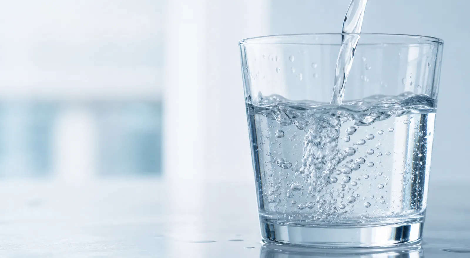 Vaso llenándose con agua cristalina